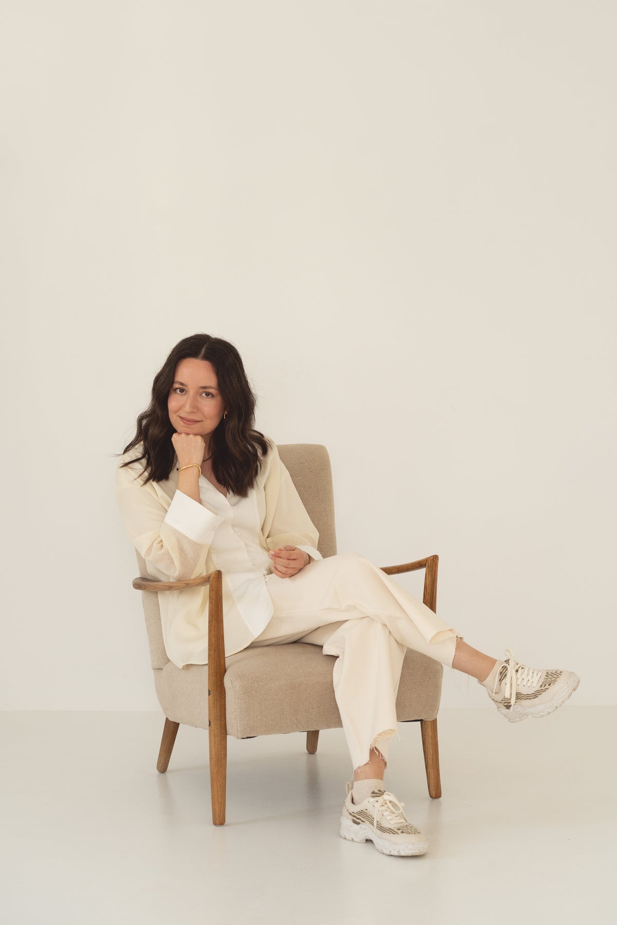 Designer Benedita Formosinho sentada numa poltrona, em conjunto claro